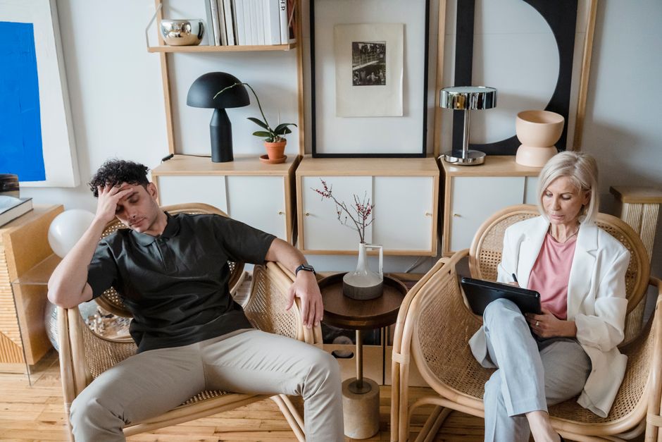 A stressed man and woman therapist in a modern consultation room.