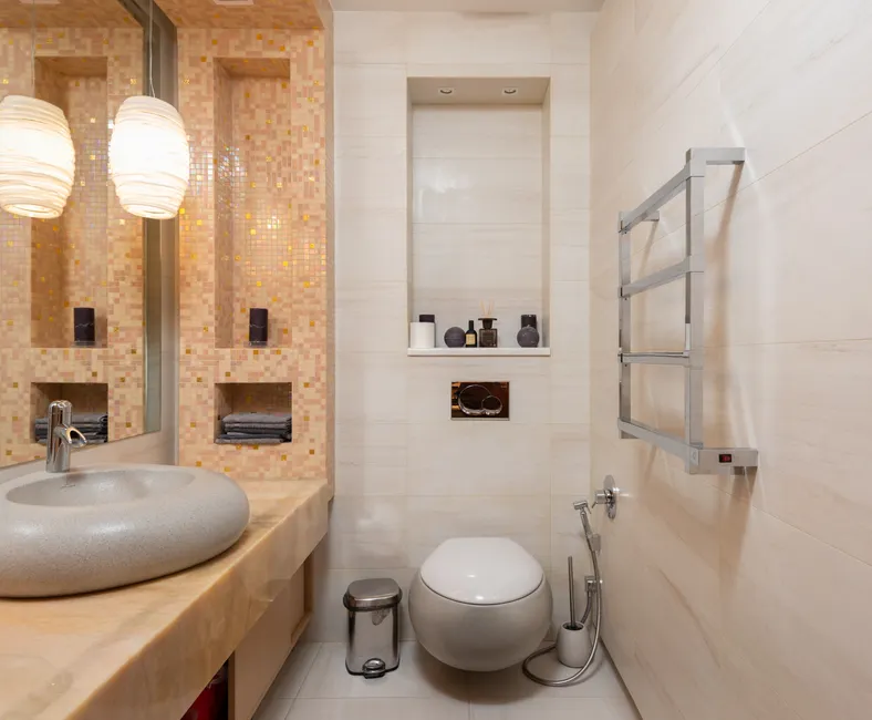 Interior of small light bathroom with ceramic sink and wall mounted toilet in modern apartment