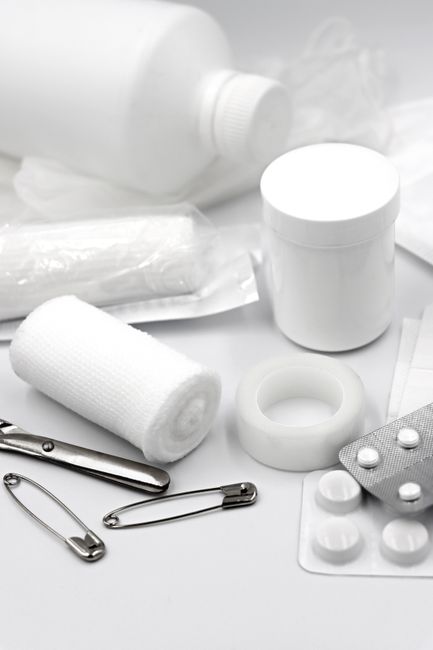 A detailed arrangement of essential first aid supplies including bandages, safety pins, and medication.