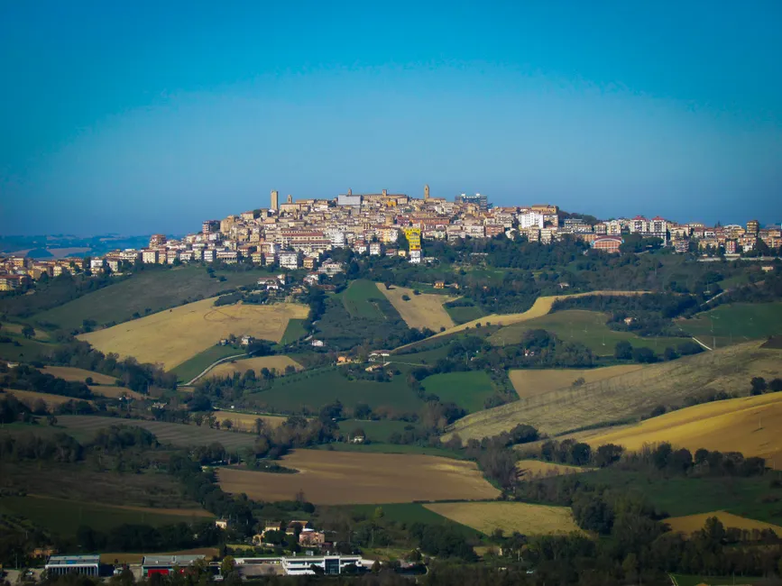 A picturesque hilltop town in Italy surrounded by lush green fields and vibrant landscapes.