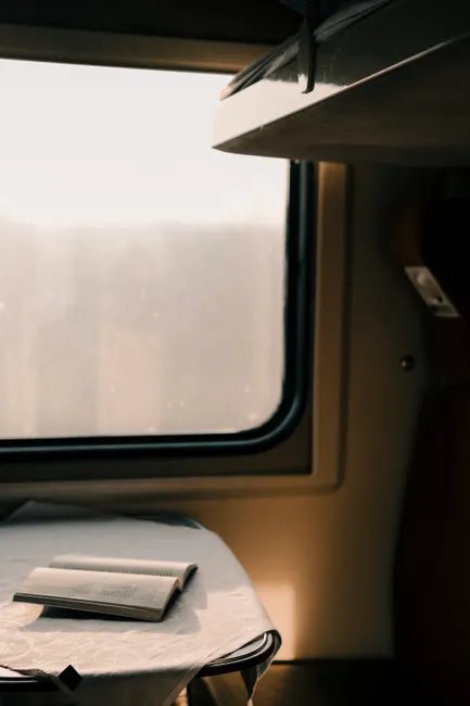 A serene train compartment showcasing an open book by the window, capturing travel tranquility.