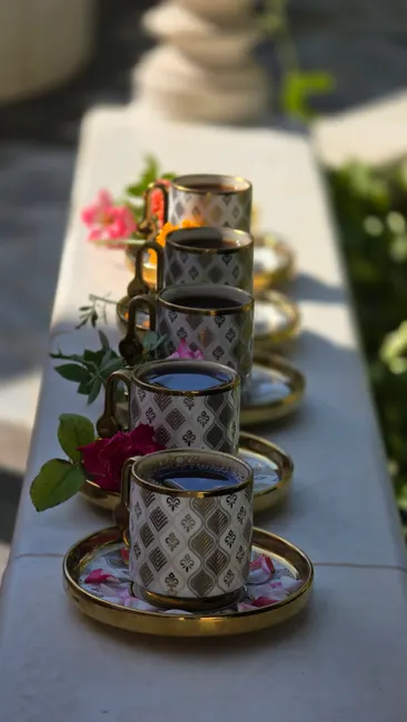 A visually appealing arrangement of ornate coffee cups with vibrant flowers on a stone surface.