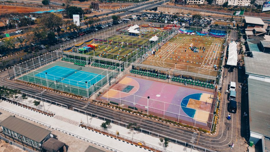 Aerial shot of colorful sports complex with tennis, basketball courts, and running tracks.
