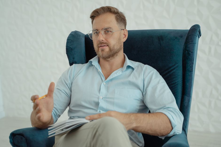 Bearded man with glasses engaging in conversation, office environment.