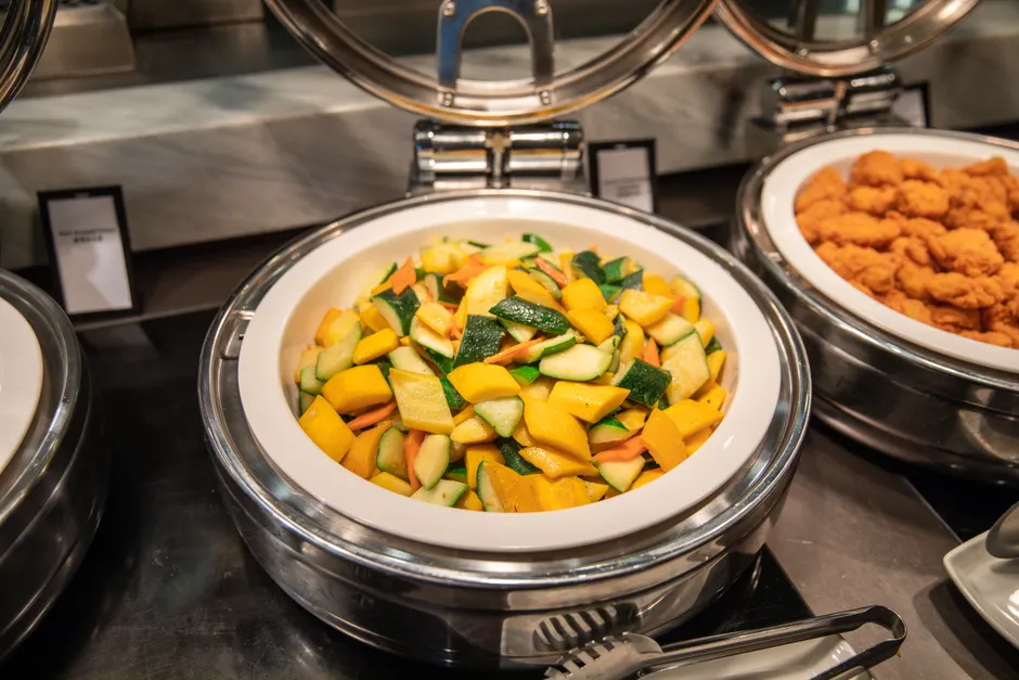 Colorful mixed vegetables in a stainless steel buffet tray, perfect for catering events.