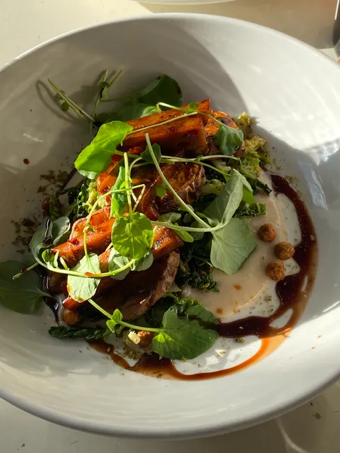 Delicious gourmet dish featuring roasted vegetables, greens, and creamy sauce.