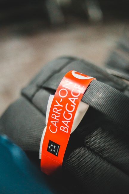 Detailed image of a carry-on baggage tag attached to a gray travel bag, indicating air travel.