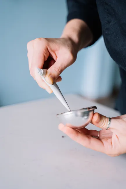 Detailed view of hands skillfully using a piping bag to fill a mold in a kitchen setting.