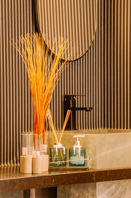 Stylish bathroom with decorative dispensers and reed diffuser on a marble counter.
