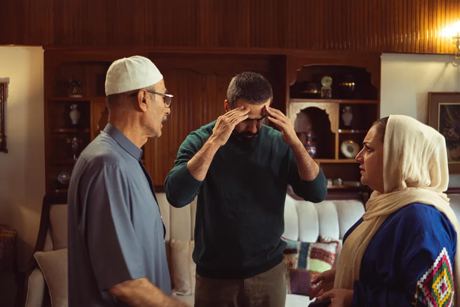 Three adults engaged in a serious discussion indoors, depicting family dynamics.