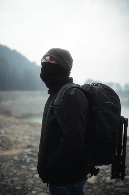 Traveler with backpack in foggy mountain terrain, capturing an adventurous morning hike.