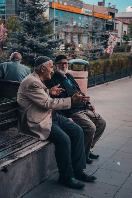 Two elderly men sharing a conversation on a park bench in Erzurum, Turkey.