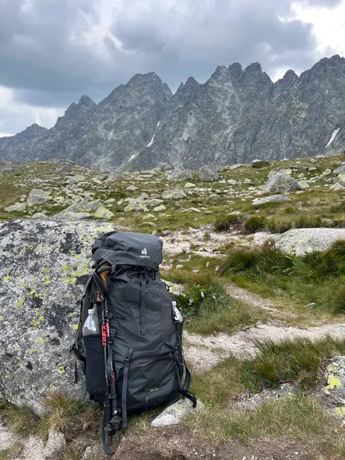 A hiking backpack resting on rocky terrain with Tatra Mountains in the background.