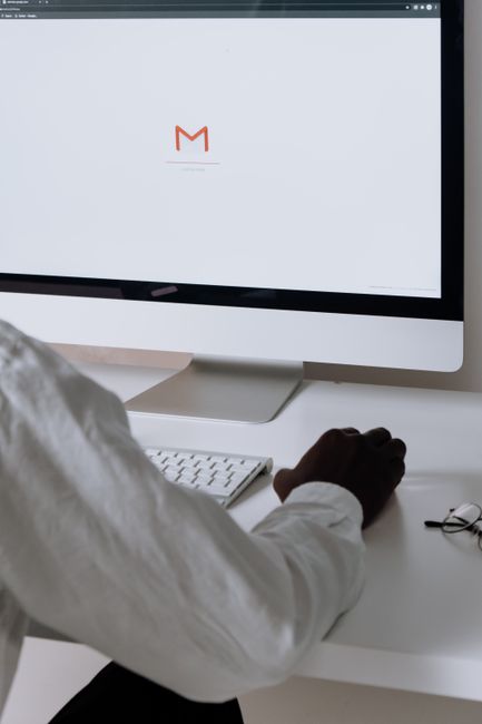 A professional in an office setting checking emails on a desktop computer with a clean workspace.
