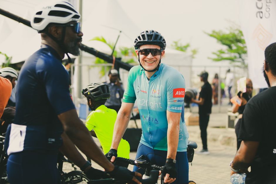 Group of cyclists in helmets and jerseys ready for a race, outdoors.